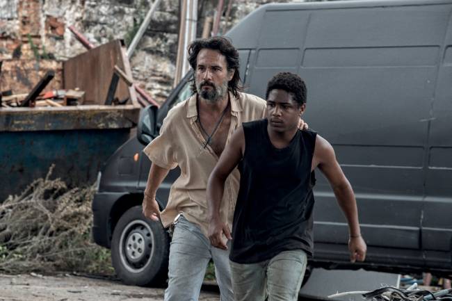 7_Prisioneiros credito aline arruda-netflix A imagem mostra Rodrigo Santoro e Christian Malheiro correndo em uma rua durante o filme 7 Prisioneiros