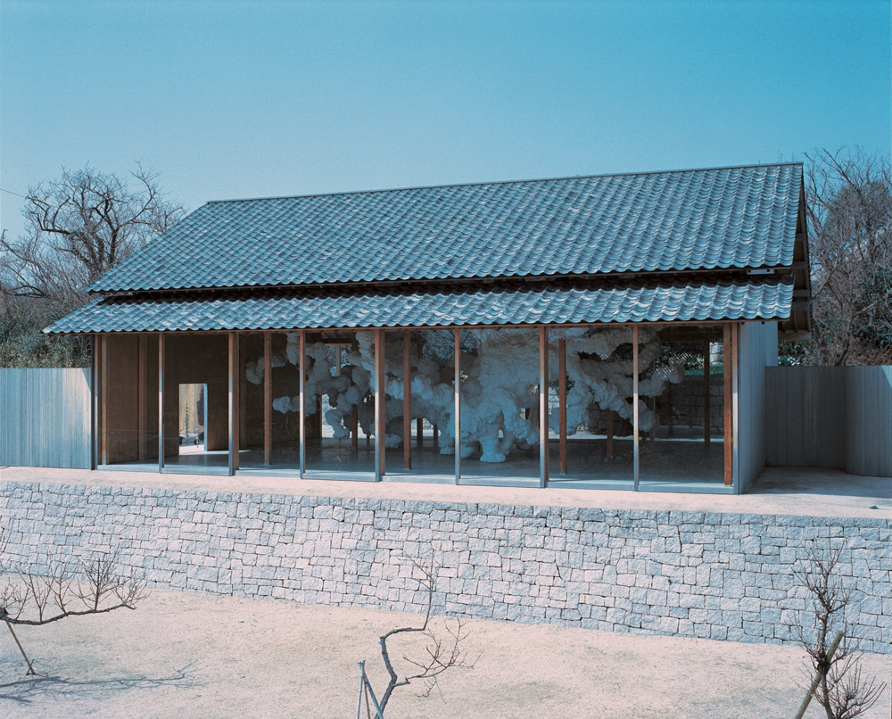 Créditos_Takashi Homma.jpg A imagem mostra uma casa, com telhado azul esverdeado, abandonada e vazia.