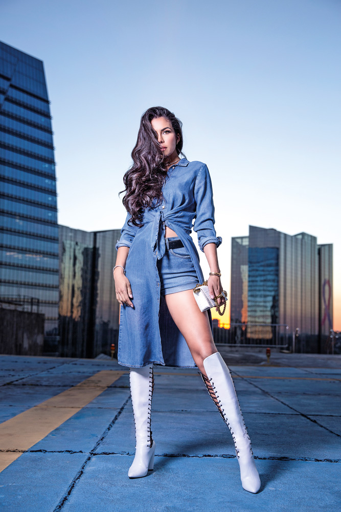 Daniela Albuquerque (Juliana Soriani-Divulgação).jpg A apresentadora Daniela Albuquerque posa de pé em espaço aberto, aparentemente um heliponto, com roupa jeans e botas brancas. Os cabelos castanhos longos cobrem metade do rosto. Ao fundo, prédios espelhados.