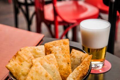Por&ccedil;&atilde;o de pastel em uma pequena cesta e copo de chope ao lado