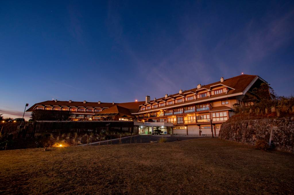 Bendito Cacao Resort & Spa (DIVULGAÇÃO) (7) Vista noturna de resort com luzes acesas e gramado em primeiro plano.