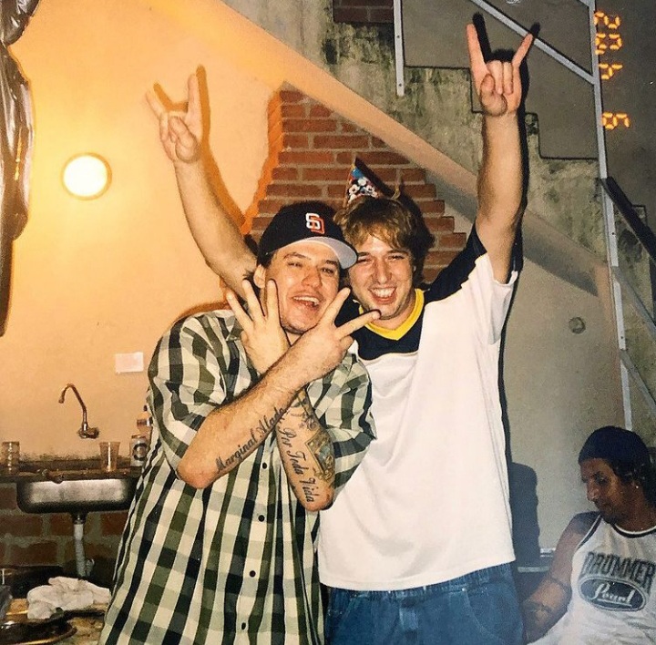 Imagem mostra dois homens sorrindo, o da esquerda de camisa listrada e o da direita de camiseta branca.