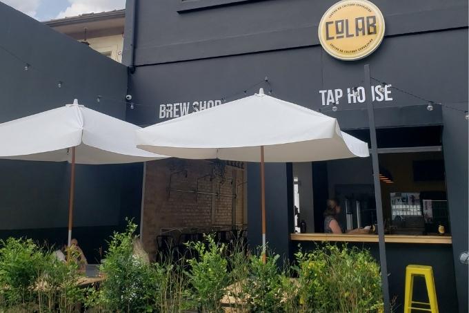Fachada pintada em preto com guarda-sóis brancos e plantas como parte da decoração