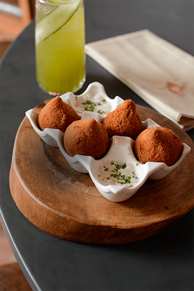Casa Rios Porção de quatro coxinhas servida em cerâmica que replica uma caixa de ovos
