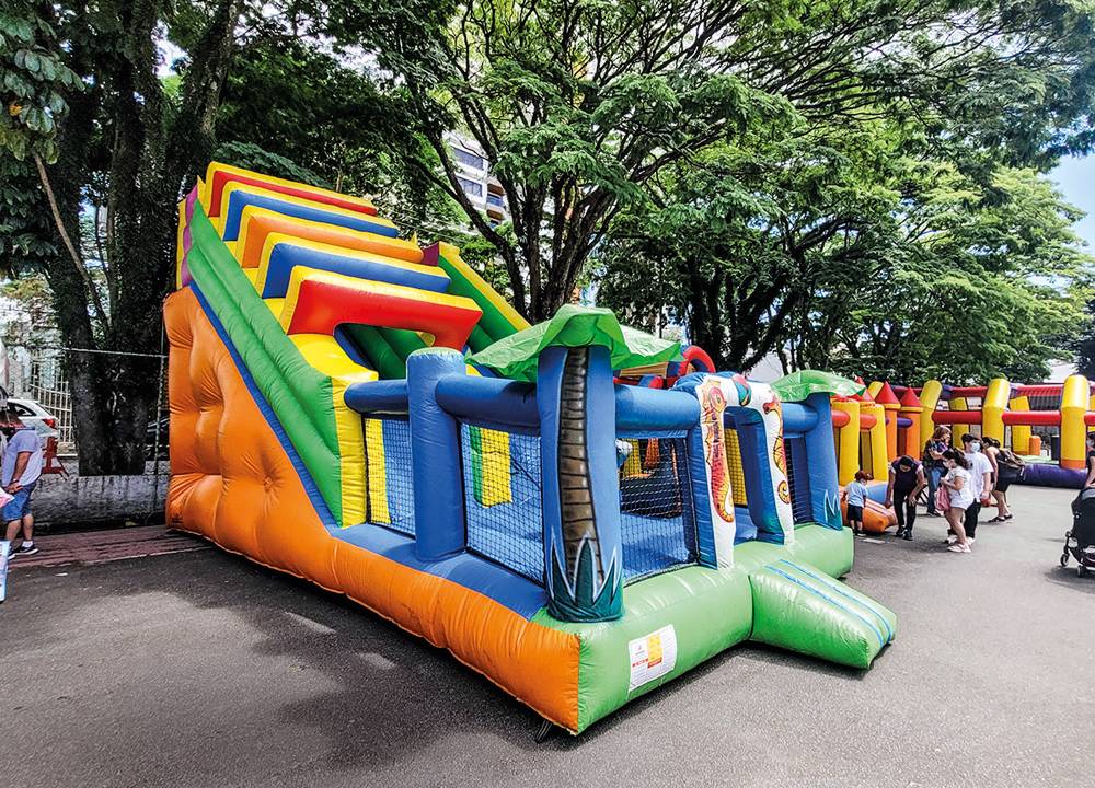 Em um parque, um brinquedão inflável está em meio a árvores