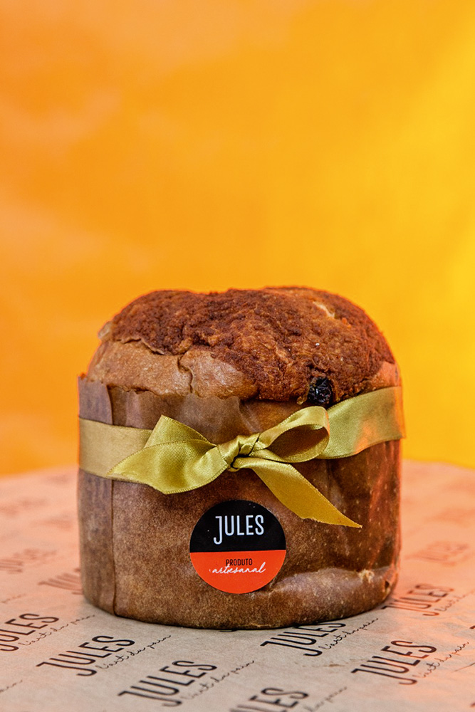 Jules L’Art du Pain Panetone decorado com laço dourado sobre fundo laranja