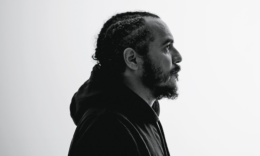 imagem em preto e branco mostra homem de perfil e casaco preto