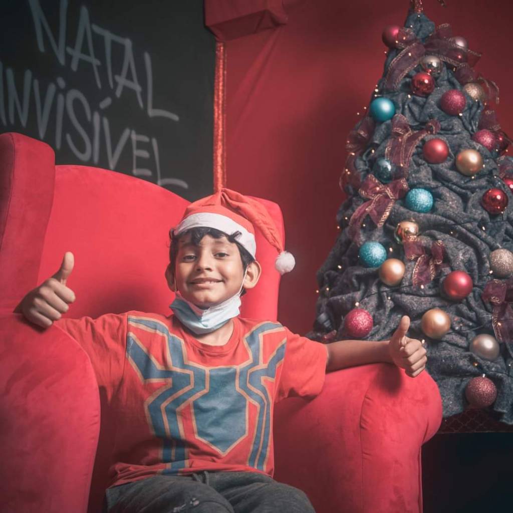 Natal Invisível Um menino sentado em uma poltrona vermelha na inauguração do