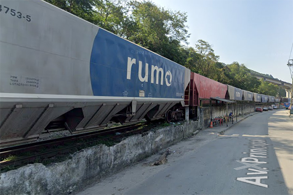 Imagem mostra foto de rua com vagões de trens que andam paralelamente ao asfalto, sem proteção de muro