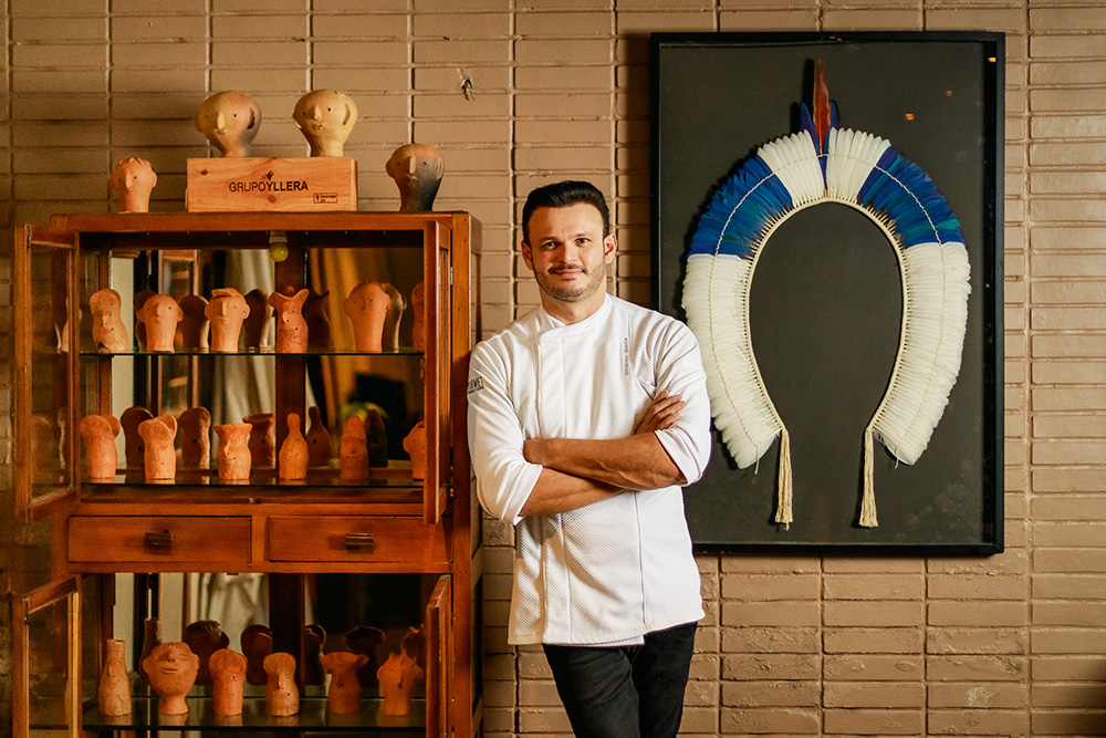 Chef posa ao lado de itens decorativos no salão do restaurante