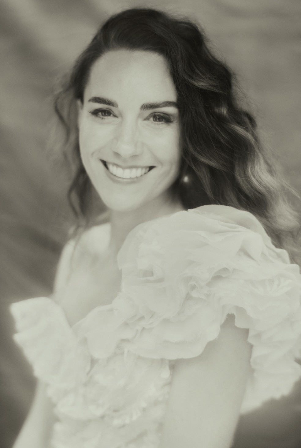 Kate Middleton Imagem em preto e branco mostra Kate Middleton de vestido branco, sorrindo