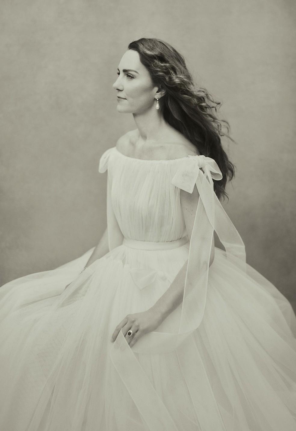Kate Middleton Imagem em preto e branco mostra Kate Middleton de vestido branco, olhando para a frente
