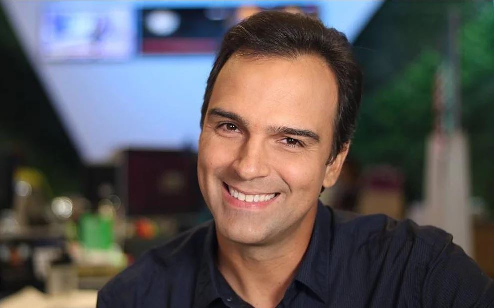 Imagem de Tadeu sorrindo. Ele veste uma camisa azul marinho