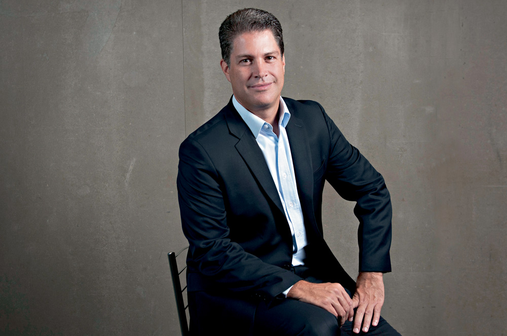 André Iasi CEO da Estapar.jpg Imagem mostra homem de terno e camisa azul clara sentado, sorrindo para a câmera.