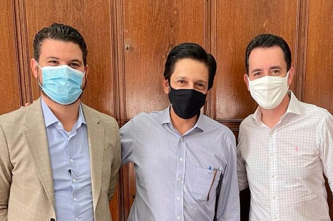 Três homens estão em pé e sorriem para a câmera