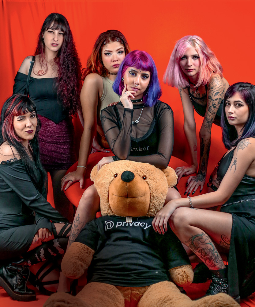 PARTY A FESTA DA PRIVACY.jpg Seis mulheres vestem preto e posam ao lado de um urso de pelúcia com a camiseta da marca. Algumas têm cabelo colorido, piercings e tatuagens.