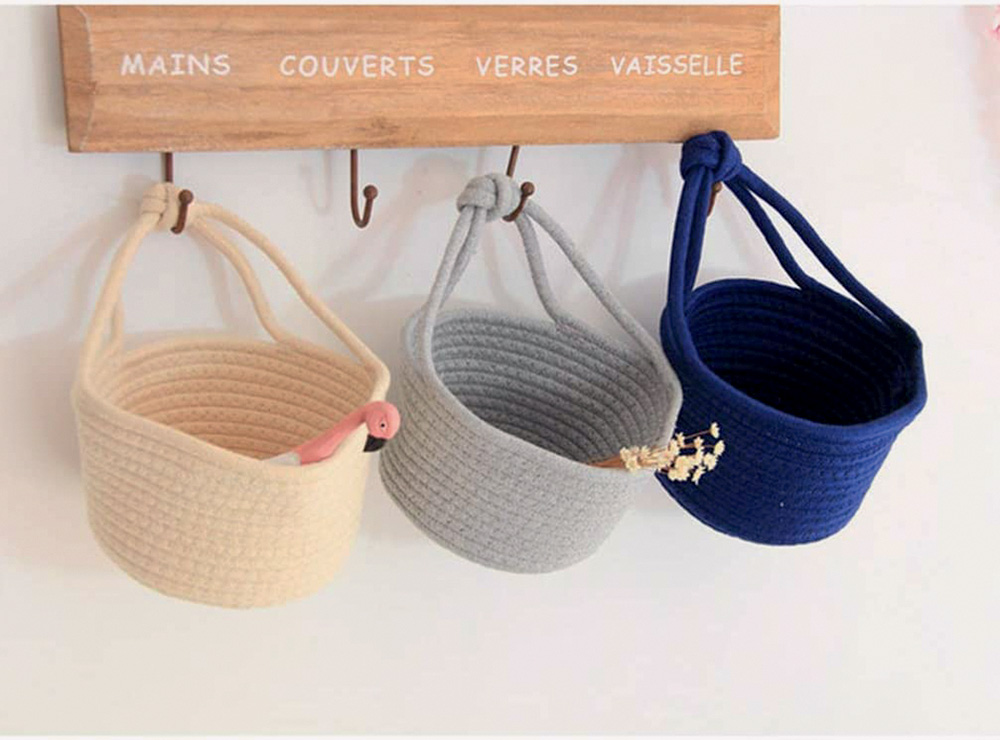 tr&ecirc;s cestos de corda de algod&atilde;o pendurados, um bege, um cinza e outro azul