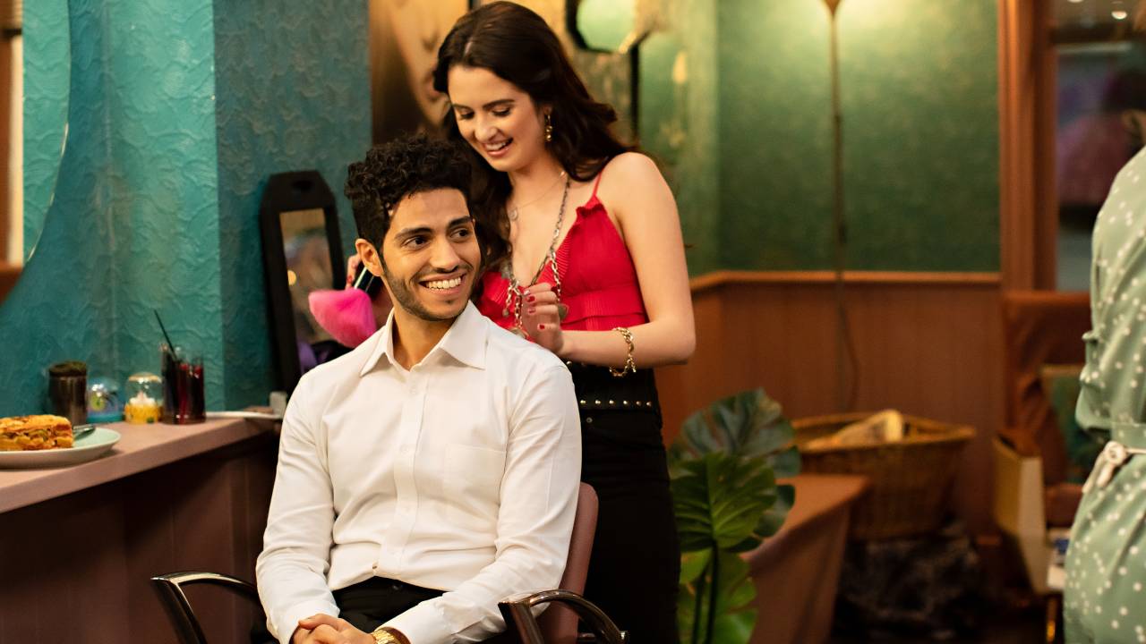 Um homem e uma mulher sorriem enquanto ela arruma o cabelo de seu par romântico