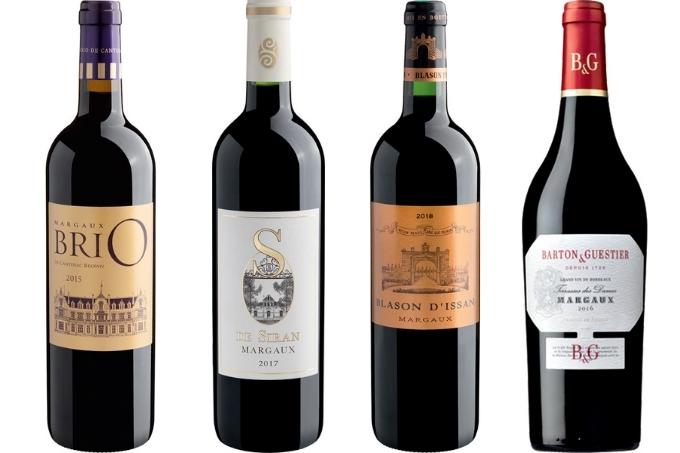 Quatro garrafas distintas de vinhos tintos sobre fundo branco