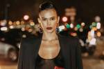 Imagem de Bruna. Ela veste uma blusa transparente preta e um blazer preto