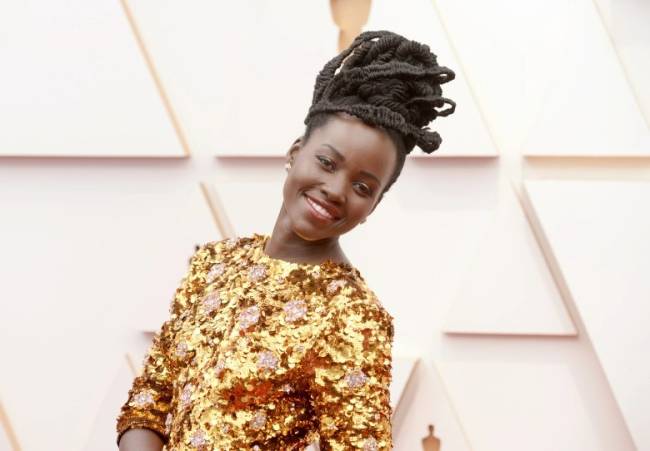Lupita Nyong’o Lupita Nyong'o, de vestido dourado, sorrindo no tapete vermelho