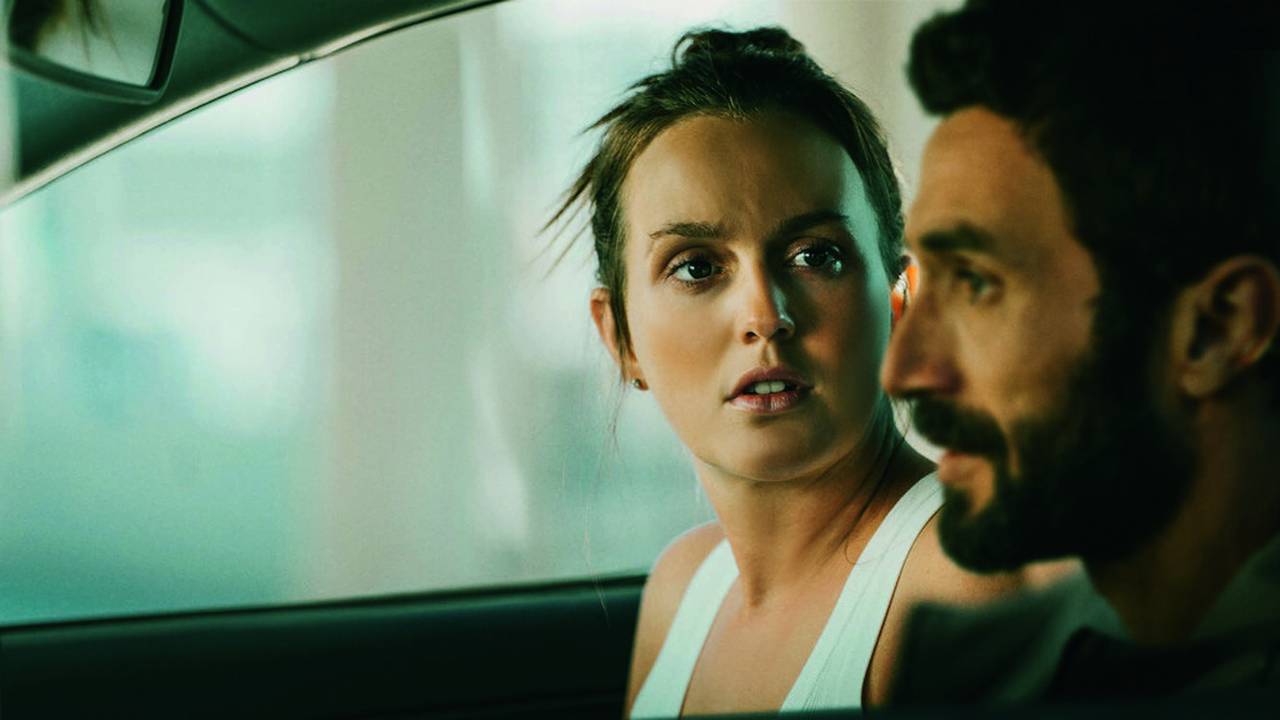 Imagem mostra mulher dentro de carro olhando para assustada para homem no banco do motorista.