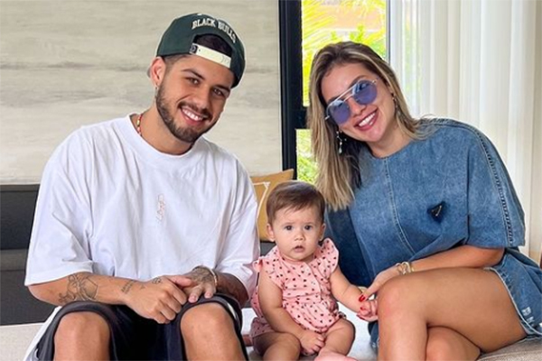 Imagem mostra família sentada em sofá, sorrindo para foto