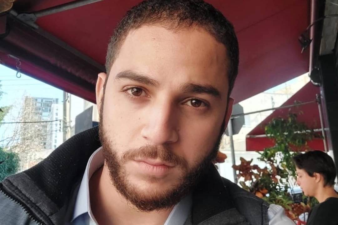 Imagem mostra Wellington em selfie embaixo de toldo de bar, sentado em cadeira