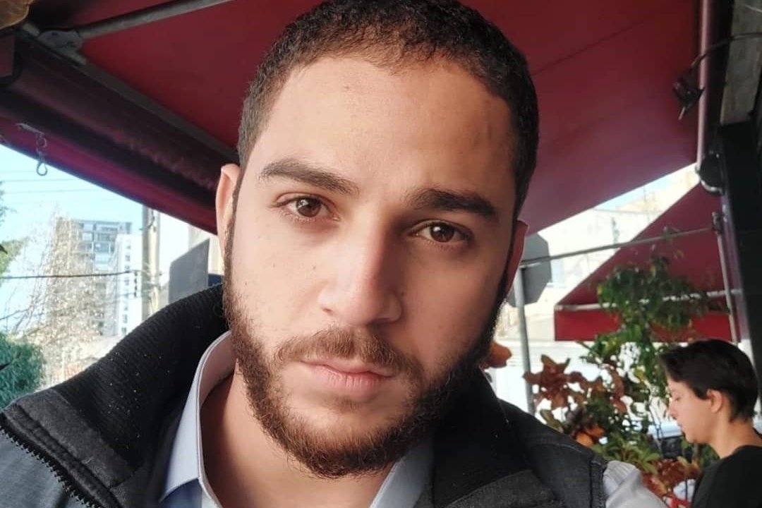 Imagem mostra Wellington em selfie embaixo de toldo de bar, sentado em cadeira