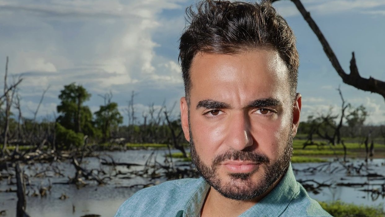 Imagem mostra homem de barba e cabelo preto olhando para a câmera, com a testa franzida.