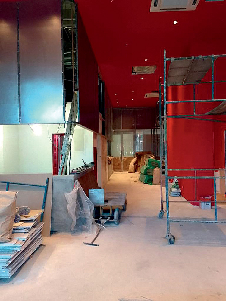 Imagem mostra ambiente de reforma, com estruturas de metal, escada e ch&atilde;o de concreto empoeirado.