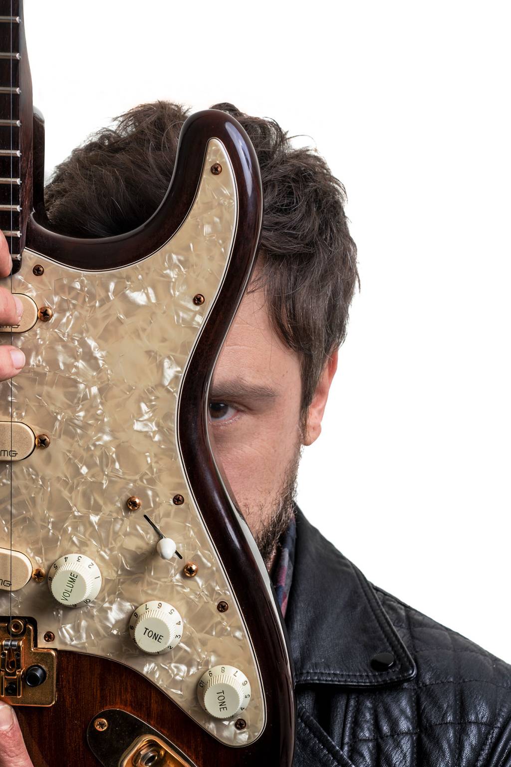 Sérgio Guizé (Lucas Marasta) Silhueta de Sérgio Guizé aparece atrás de guitarra com detalhes brilhantes.