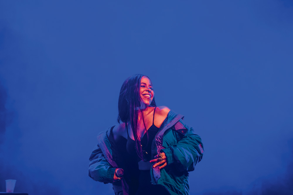 Imagem mostra mulher sorrindo sobre fundo azul.