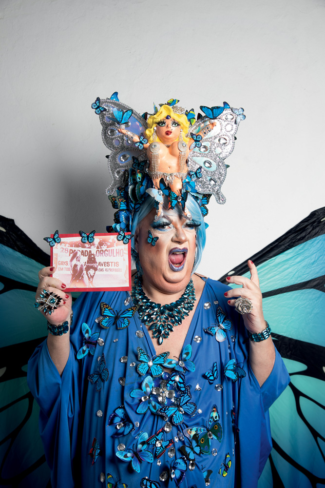 lgbtKAKADIPOLLY6 – crédito Leo Martins.jpg Imagem mostra pessoa com figurino azul e uma foto antiga na mão