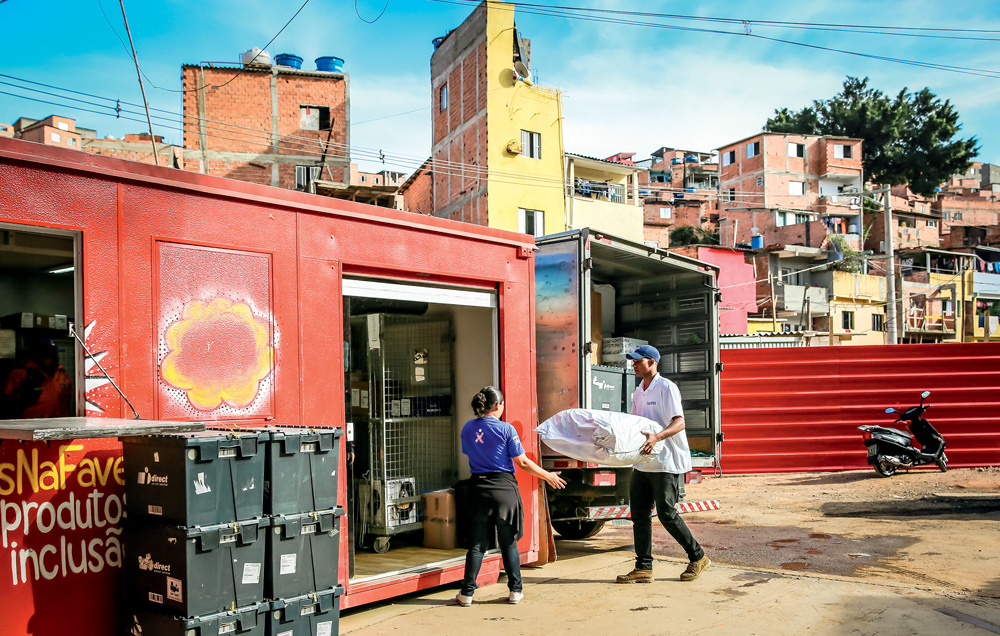 FAVELAEXPRESS_2.JPG Dois trabalhadores, um homem e uma mulher, descarregam um caminhão e um contêiner com pacotes e caixas, em Paraisópolis