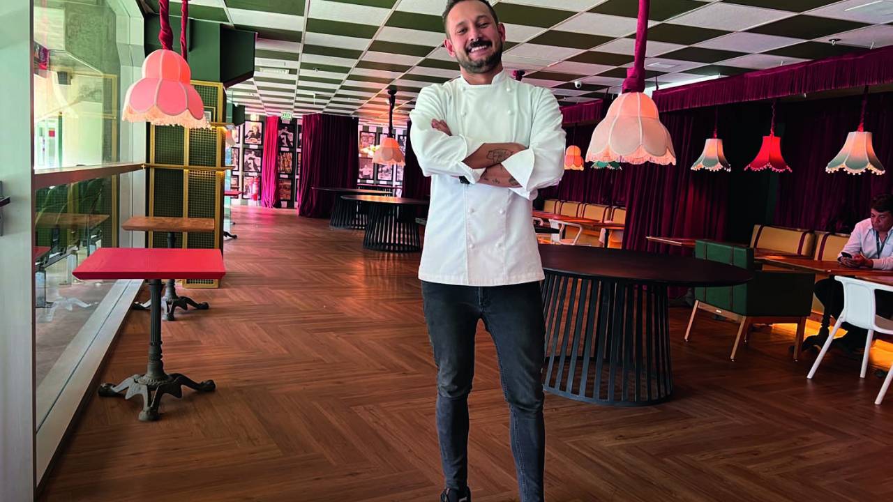 Chef Giovanni Renê posa em frente ao salão do La Coppa. Ao fundo, o salão e as mesas do restaurante.