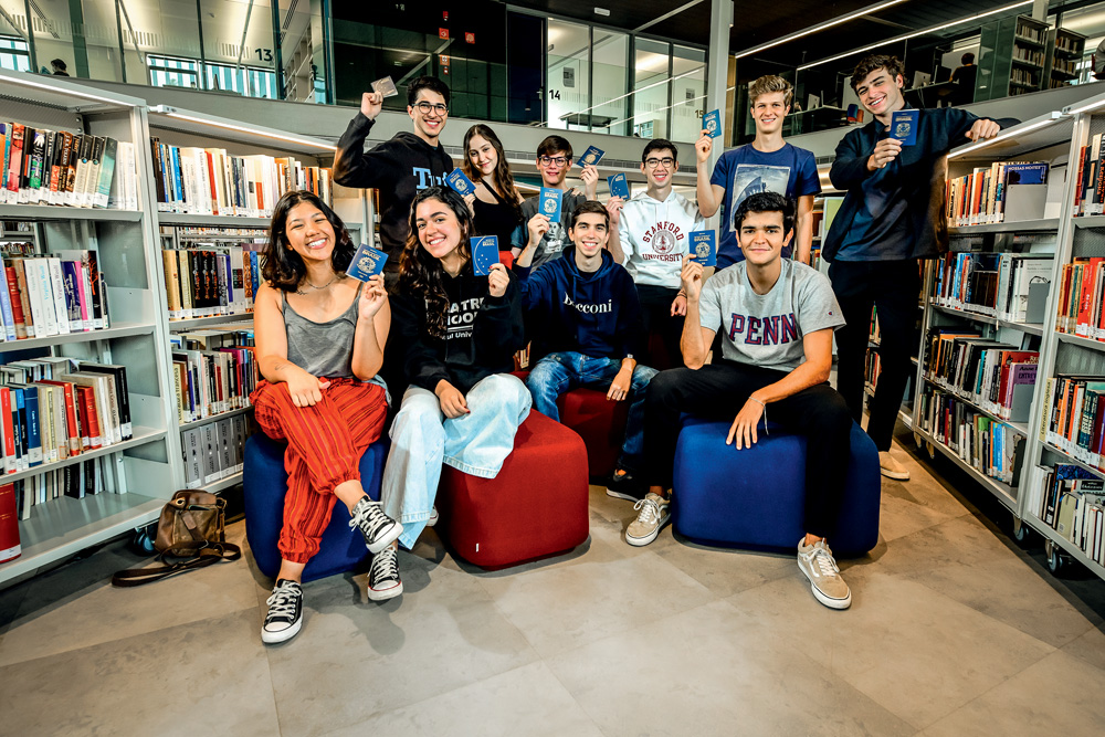 Alunos do Colégio Santa Cruz seguram passaportes na mão e sorriem