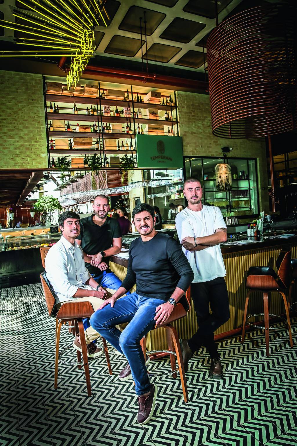 LOSPRIMOS_3.JPG Imagem mostra quatro homens sorrindo sentados em bar de restaurante