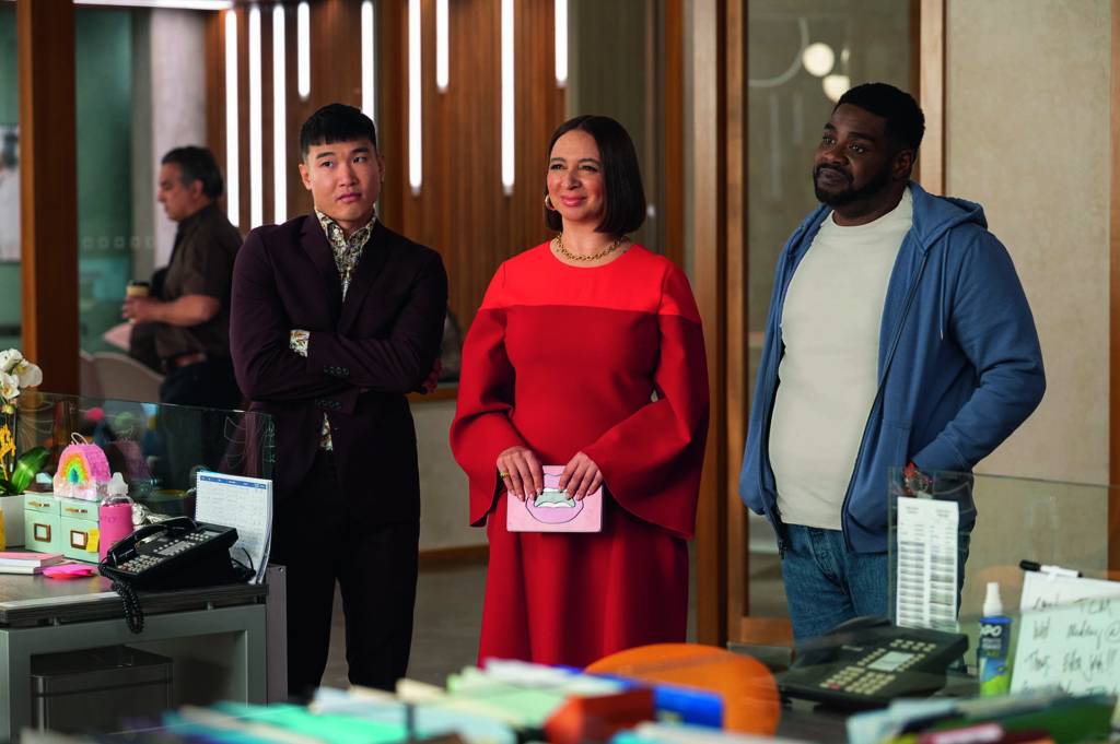 fortuna – cred appletv+.jpg Imagem mostra sala com mulher de vestido vermelho entre dois homens. Ela sorri.