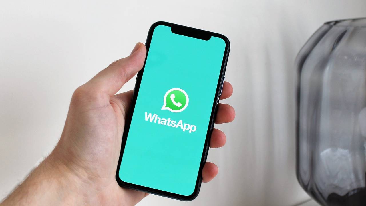 Pessoa segurando um celular. Na tela do aparelho, aparece o logo do aplicativo WhatsApp.