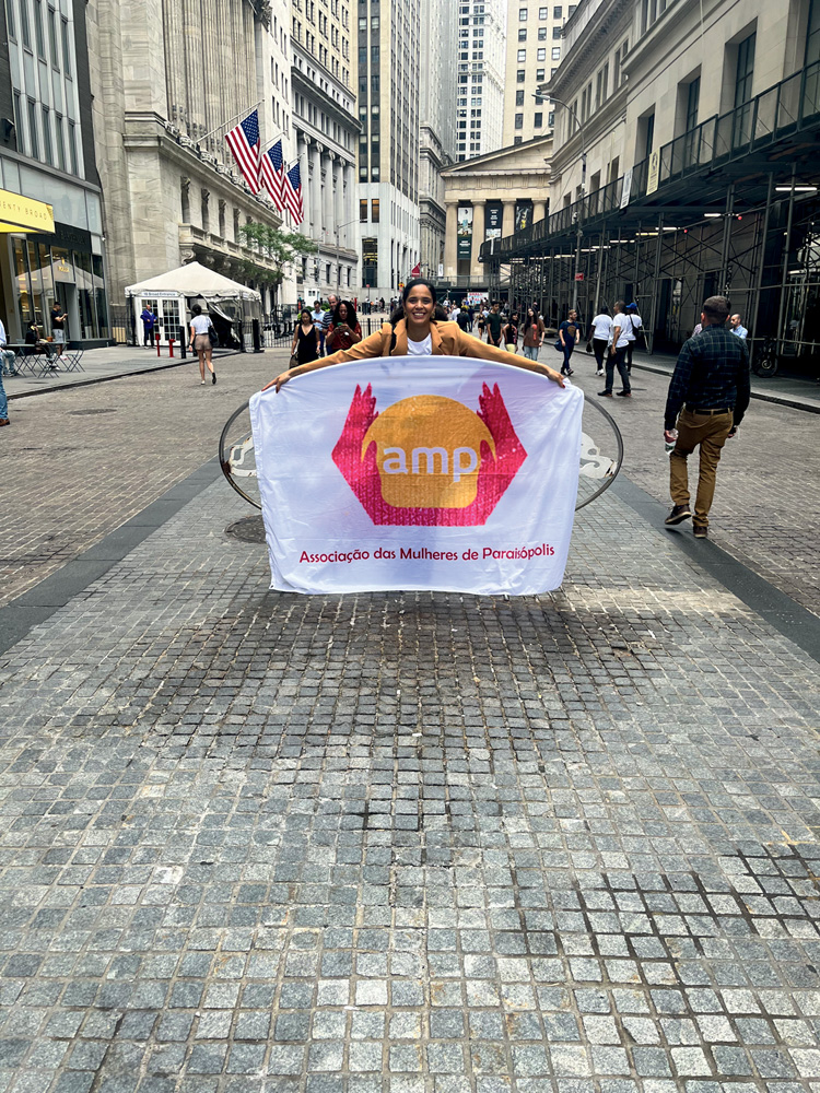 AssociacaoMulheresParaisopolis.jpg Flávia Rodrigues segura uma faixa em uma rua de Nova Tork