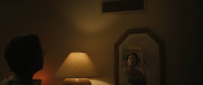 Dahmer Netflix Mulher se olha no espelho em quarto escuro