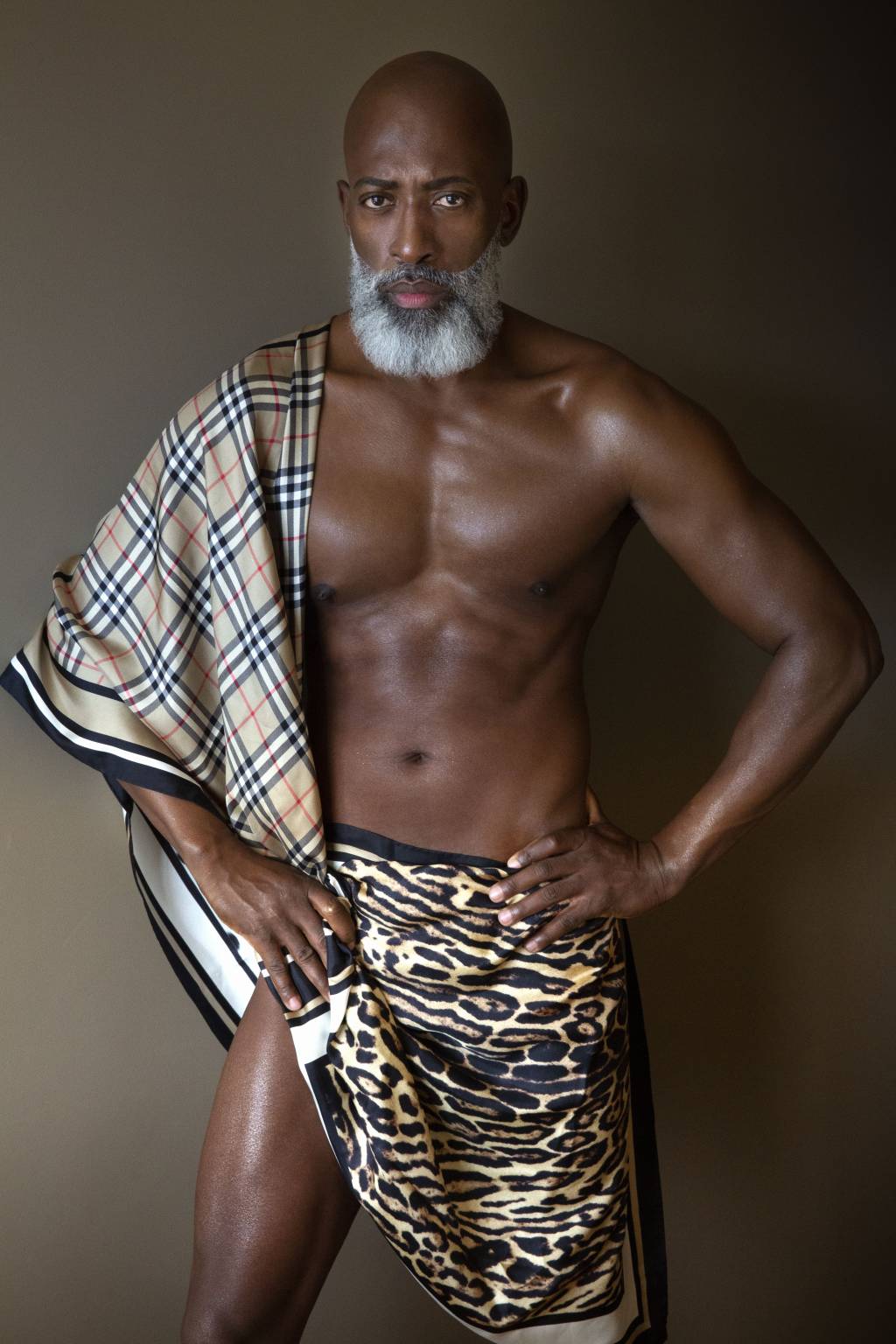 DI PRIMO (Fernando Torquatto-Divulgação) Homem sem camisa posa com mãos na cintura, um lenço quadriculado e barba branca.