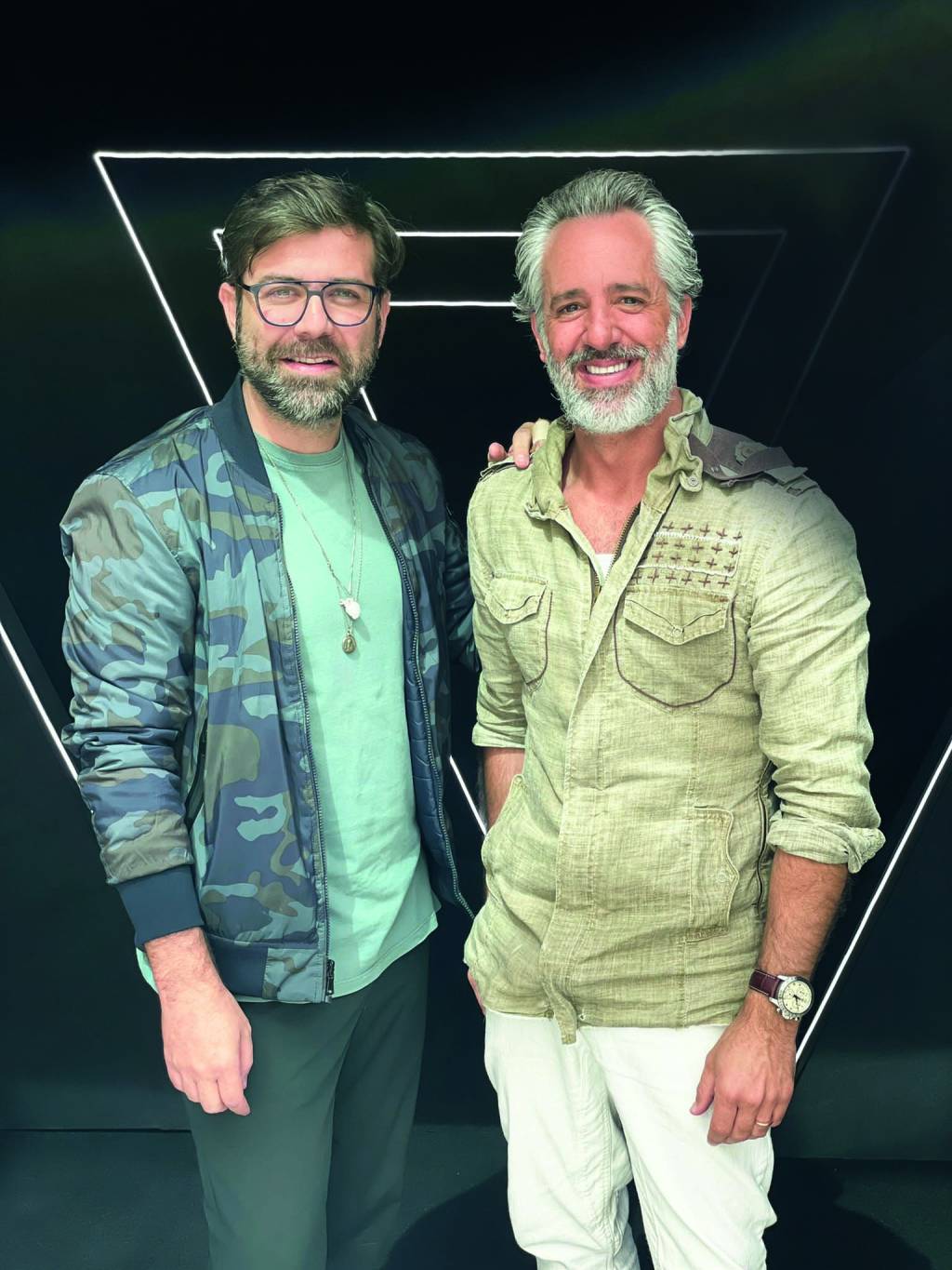 Fábio Maca (de óculos) e Ike Levy (grisalho) (RODRIGO TREVISAN-DIVULGAÇÃO) Fábio Maca e Ike Levy posam lado a lado. À esquerda, com óculos de grau, barba cinza, jaqueta e camiseta verde. À direita, grisalho de barba com camisa clara.