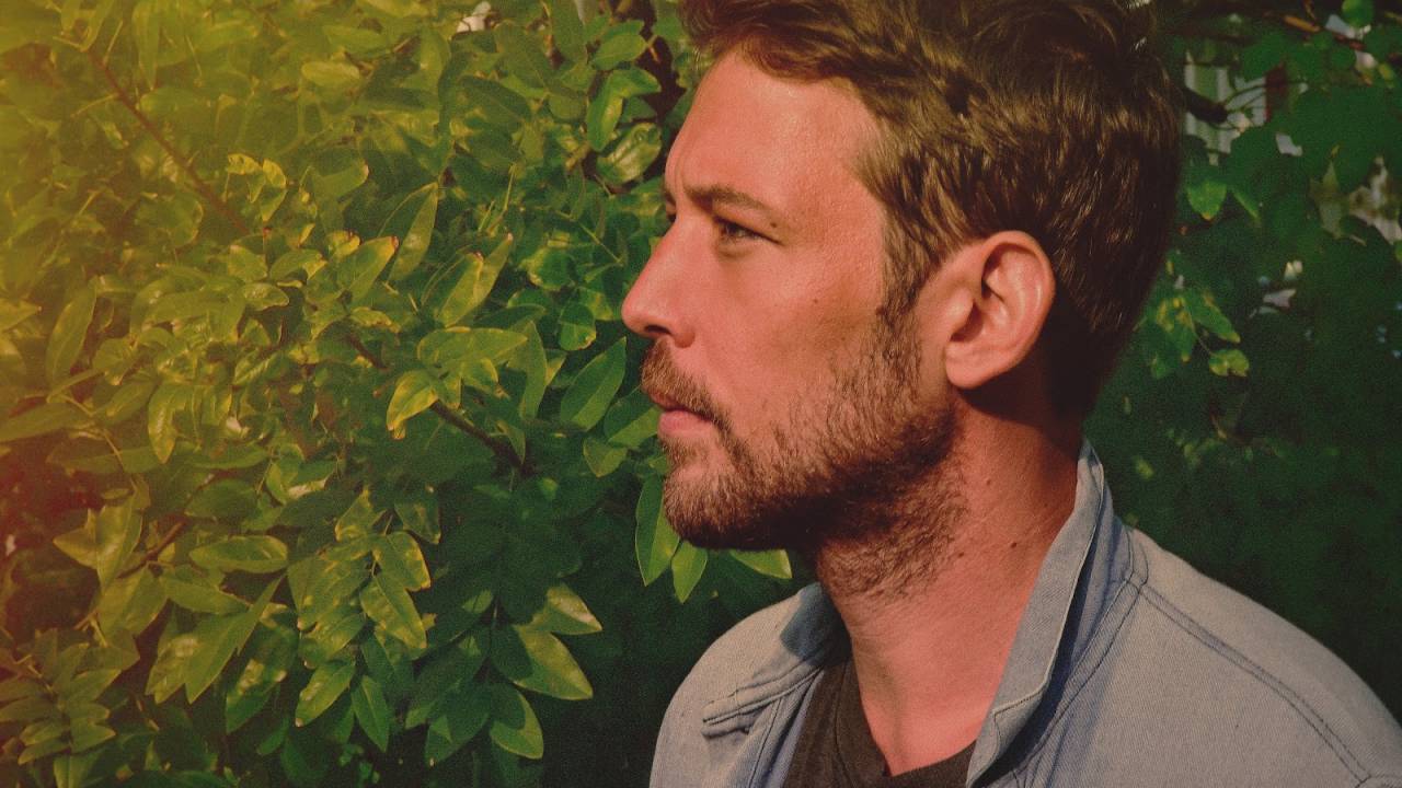 Imagem mostra homem de perfil com mato ao fundo.