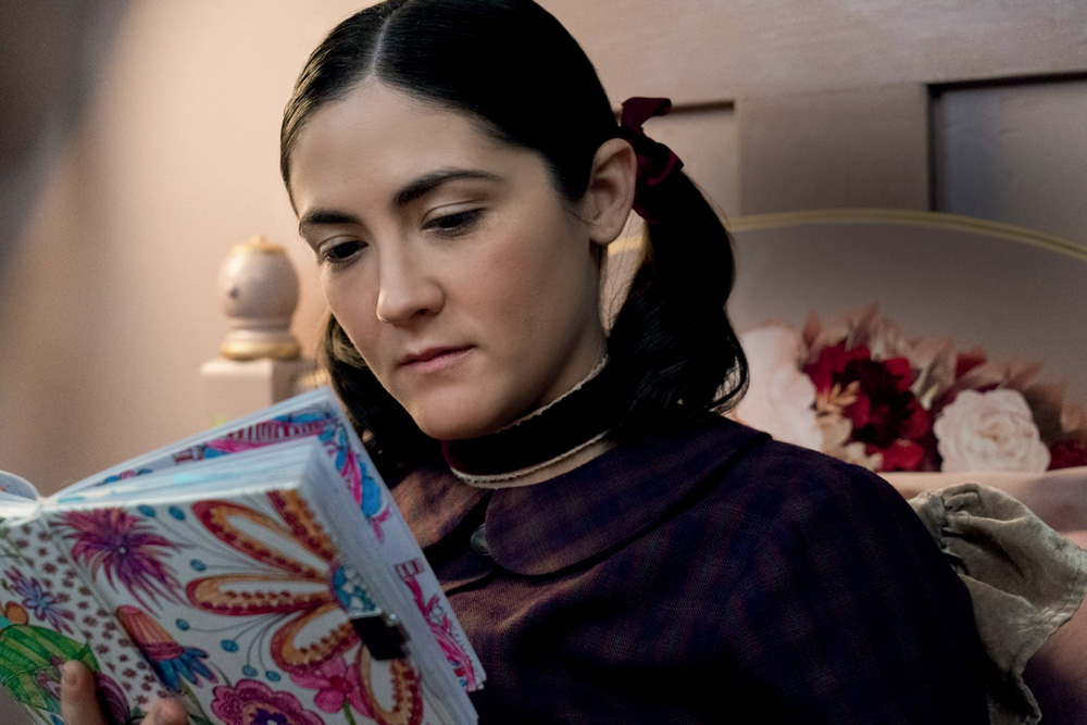 Imagem mostra mulher de cabelo preso, lendo livro.