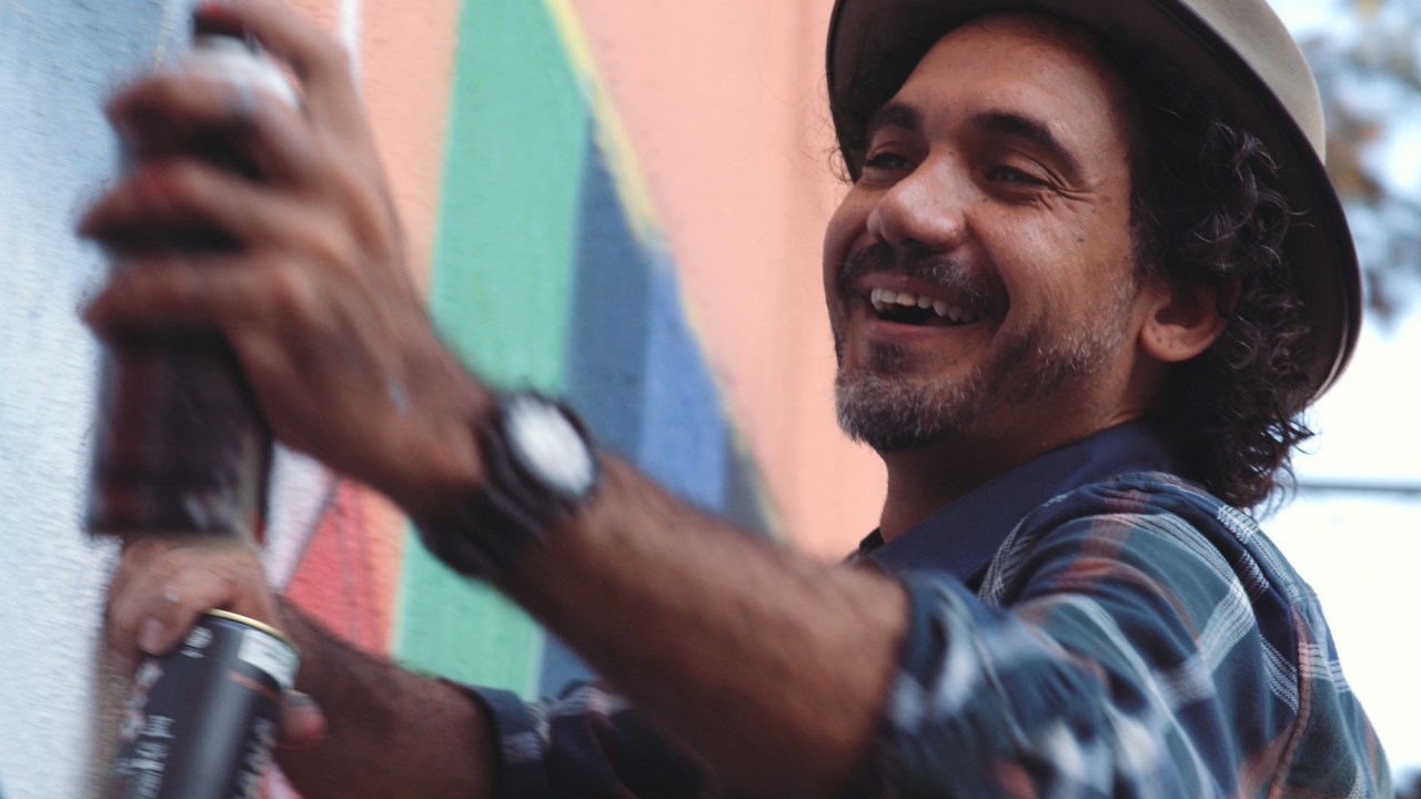 Muralista Eduardo Kobra sorri enquanto pinta