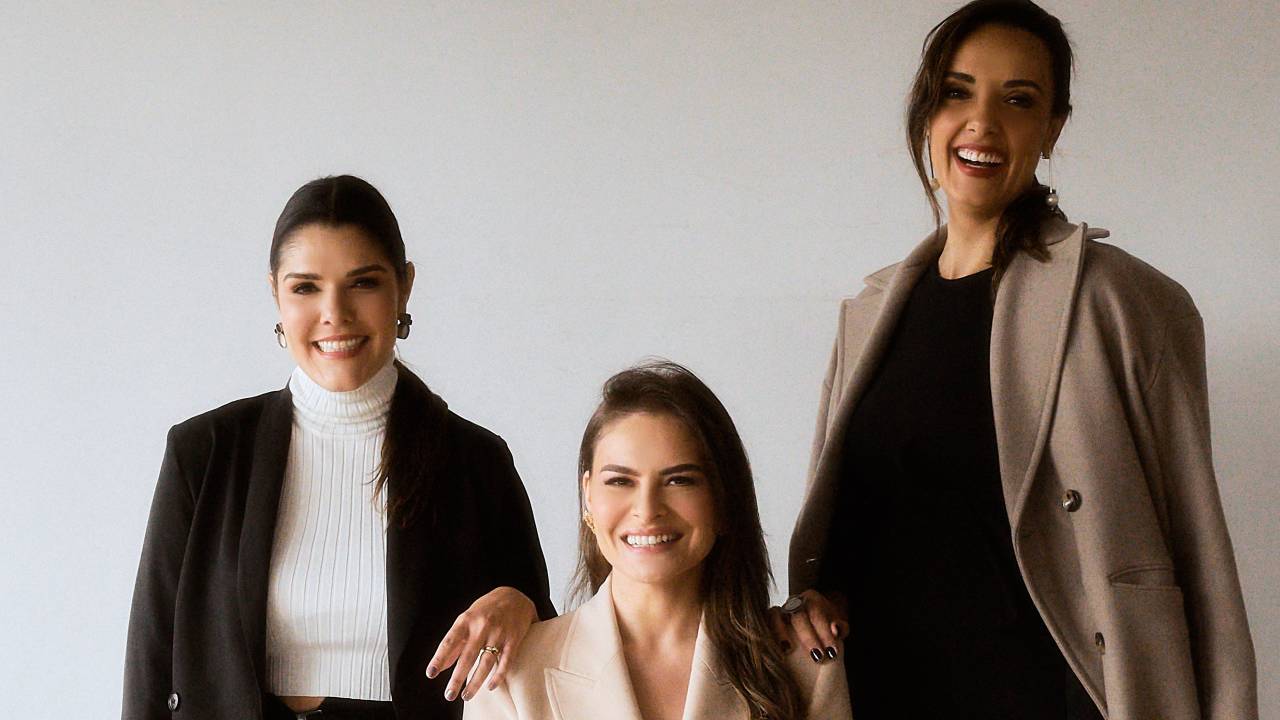 Três mulheres de blazer posam lado a lado.
