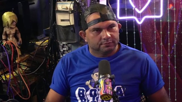 Foto de Bill Morais, usando camiseta azul e boné, no estúdio do podcast