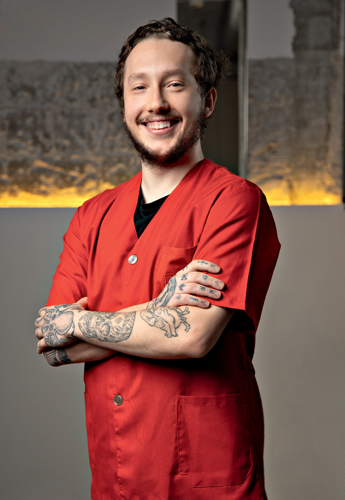 Imagem mostra homem sorrindo, vestindo roupa vermelha, com os bra&ccedil;os cruzados